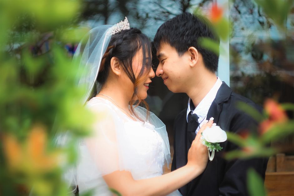 A joyful bride and groom sharing a tender moment in a lush outdoor setting.