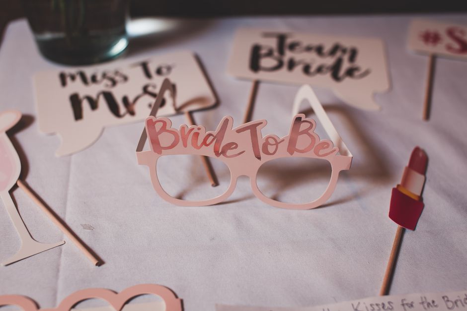 Photo booth props for a bridal shower featuring glasses and signs for the bride-to-be, creating a festive atmosphere.