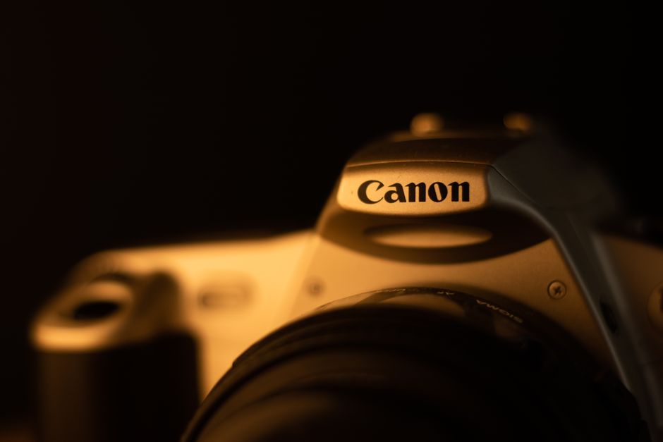 Artistic closeup of a vintage Canon camera in low light, showcasing detail and shadow.