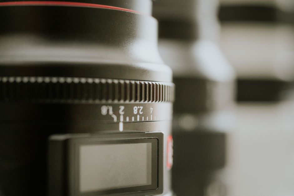 Detailed close-up of a camera lens focus ring with blurred background, showcasing photography equipment.