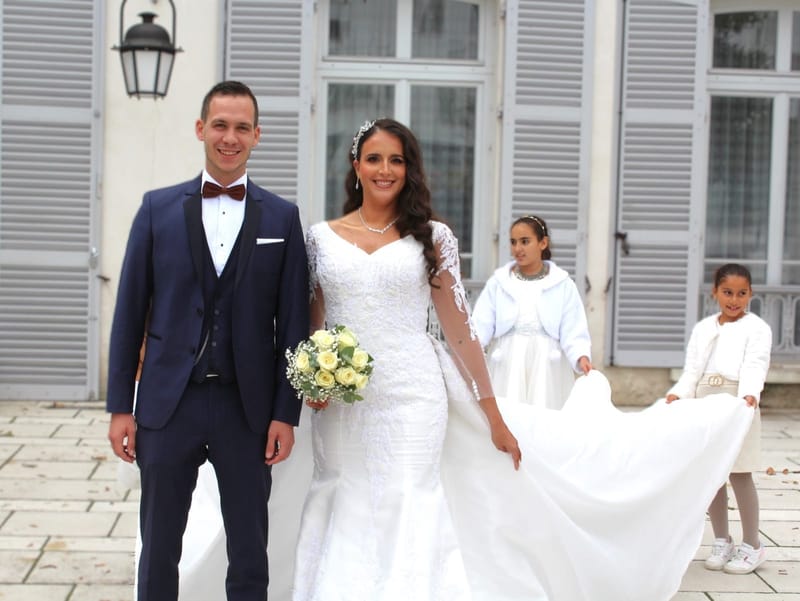 Deux enfants portent la traîne de la mariée devant la mairie