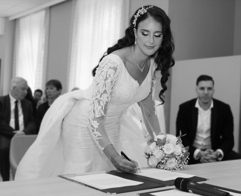 La mariée signe le registre pendant la cérémonie civile, en noir et blanc